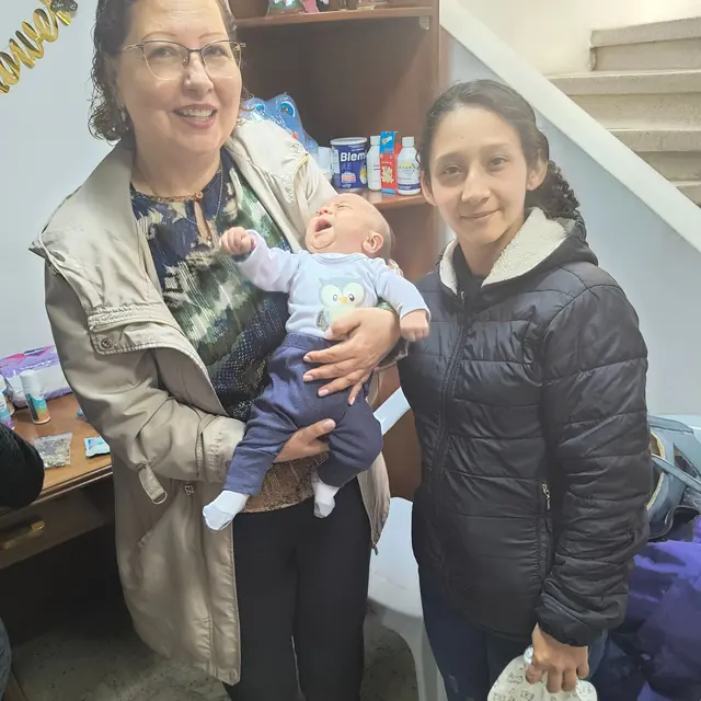 Una voluntaria y una mamá con su bebé en la sede