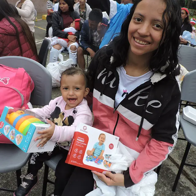 Mamá sonriente con su bebé y sus regalos